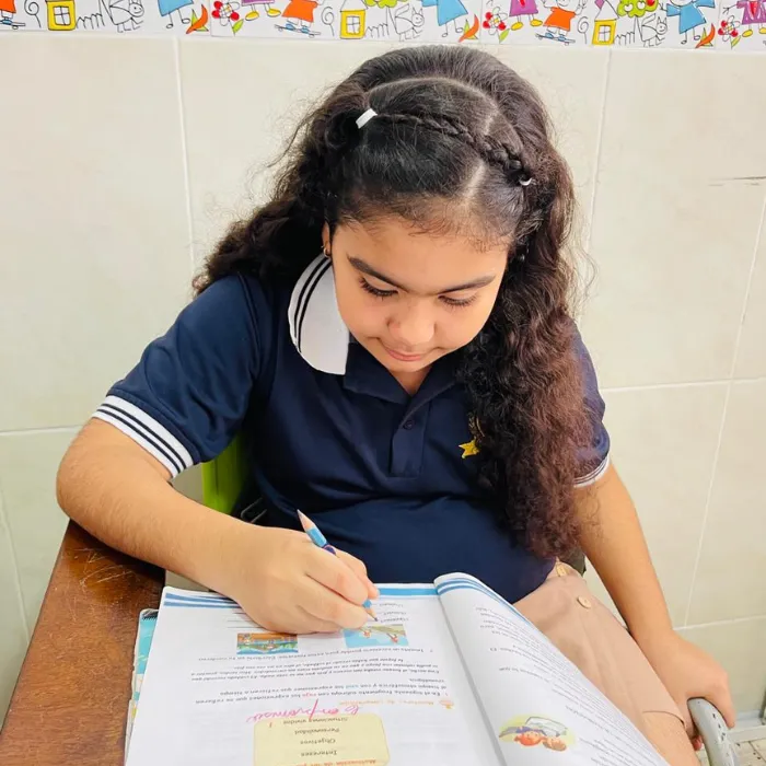 Estudiante del Gimnasio Campestre escribiendo en un libro de actividades